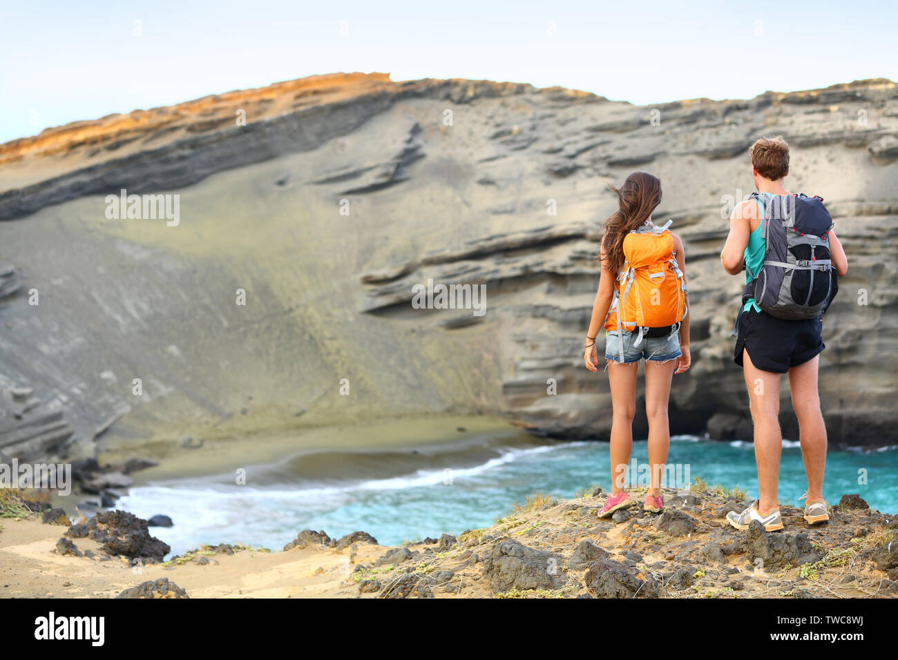 Les randonneurs - couple voyage touristes randonnée sur Hawaii. Balades touristiques backpackers sur plage de sable vert, Papakolea sur Big Island, Hawaii, USA. Young happy couple voyageant avec sac à dos. Banque D'Images