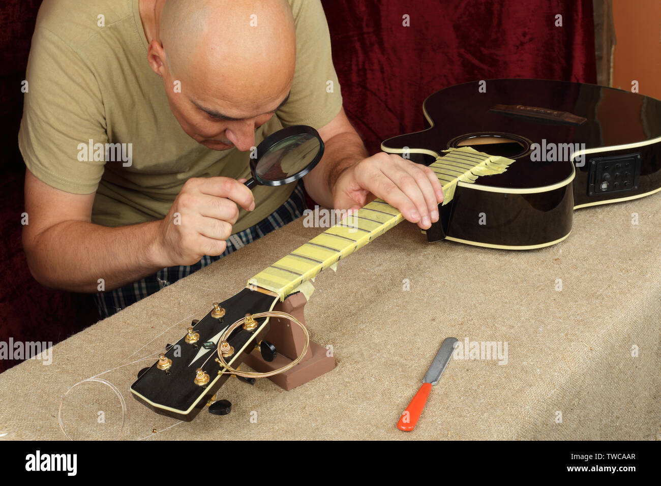 Réparation guitare instrument de musique et le service de contrôle des travailleurs - affiner l'outil bridge l'écrou de l'amplificateur de guitare acoustique noir Banque D'Images