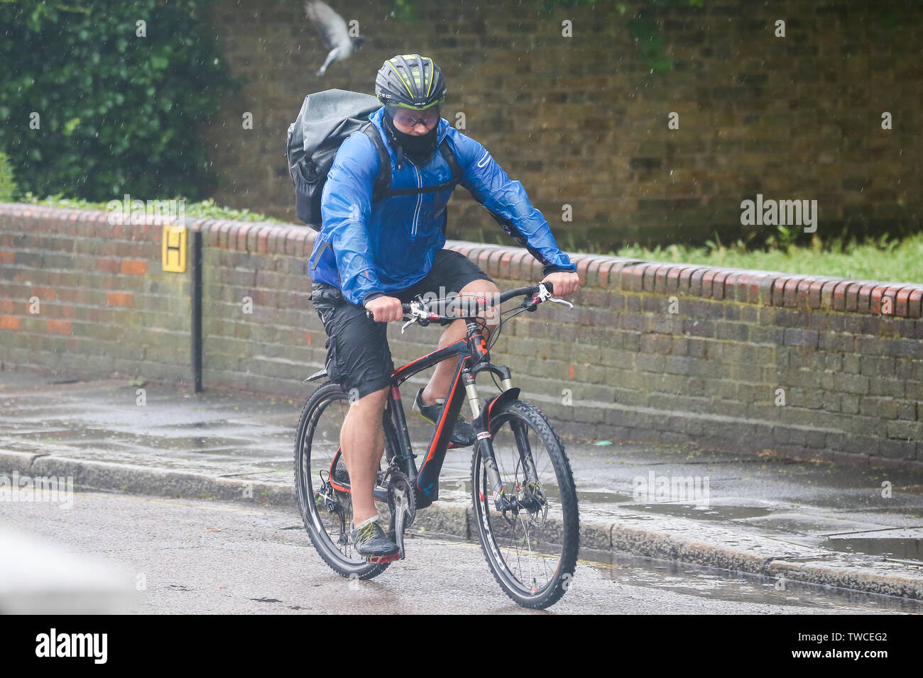 Un cycliste monte un vélo pendant l'averse lourde à Londres. Banque D'Images