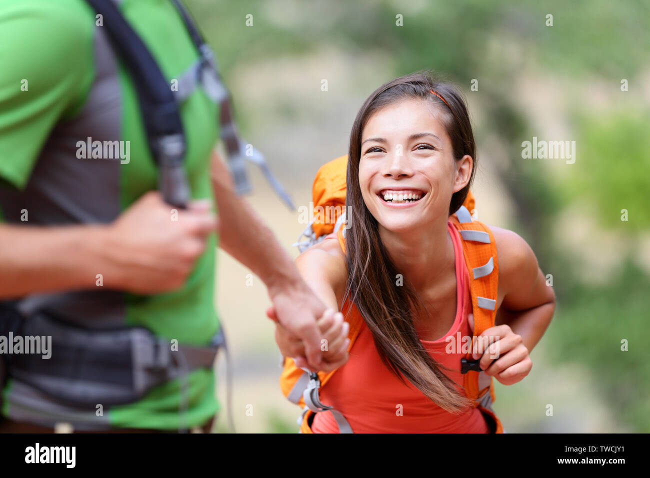 Coup de main - randonnée femme obtention d'aide à la randonnée smiling happy surmonter un obstacle. Vie active hiker couple voyageant. Beautiful smiling mixed race Woman modèle féminin asiatique. Banque D'Images