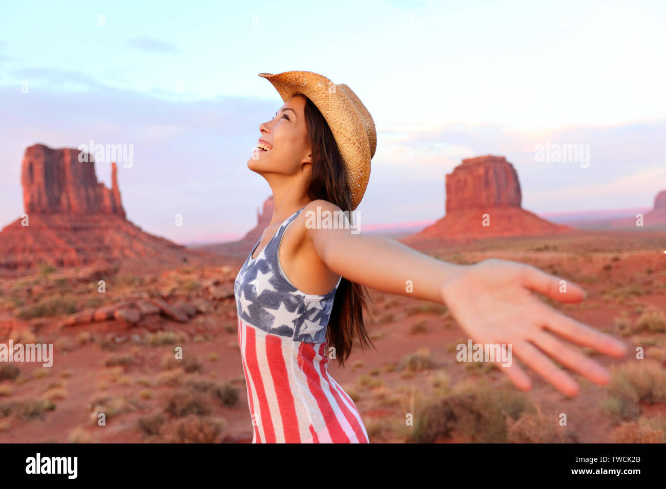 Cowgirl - femme heureuse et libre dans la Vallée de Monument wearing cowboy hat avec bras tendus dans la liberté concept. Beautiful smiling young woman outdoors multiraciale, Arizona, Utah, USA. Banque D'Images