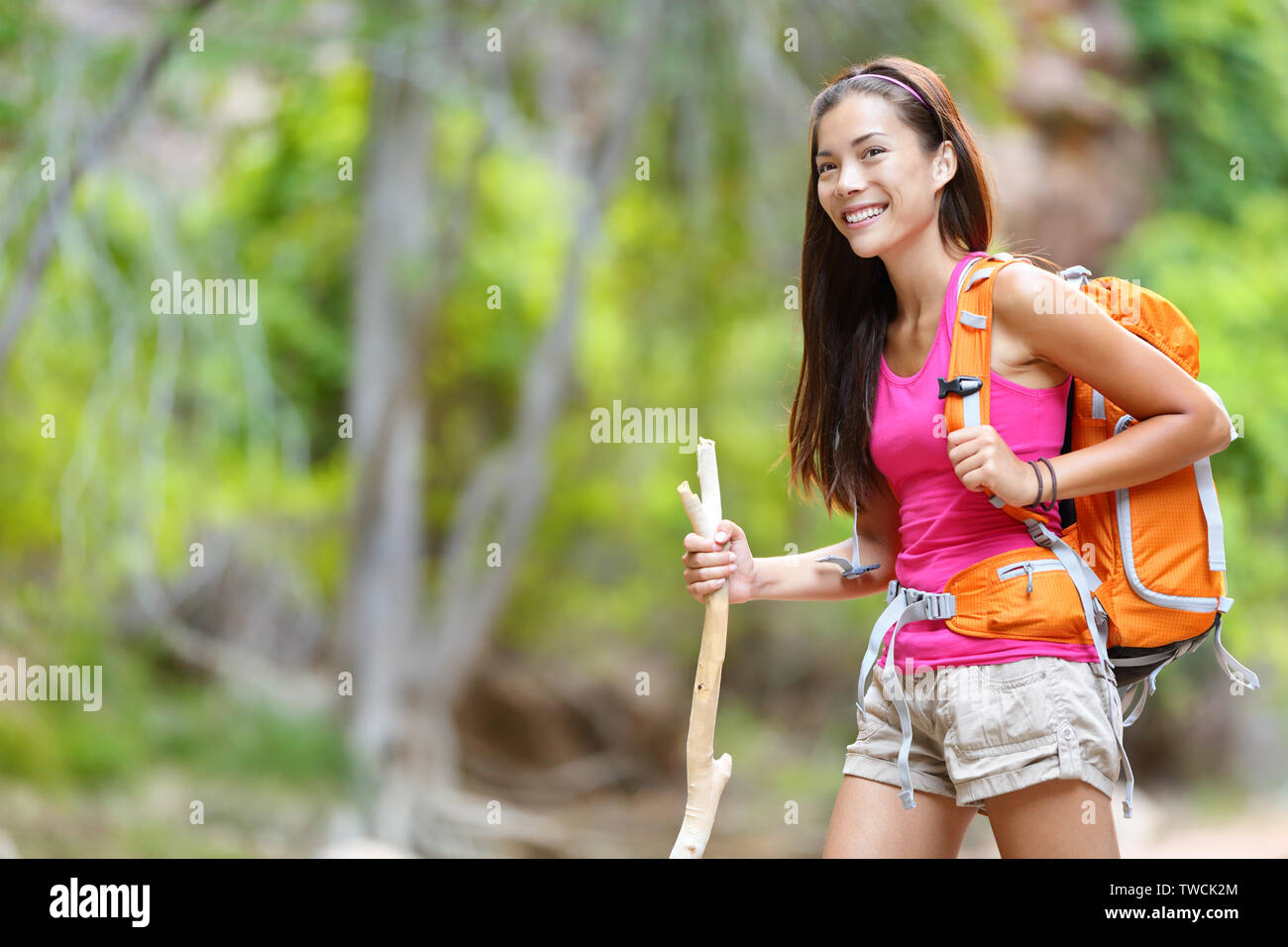 Asian woman hiker randonnées en forêt debout avec sac à dos et bâton de marche en bois smiling happy healthy active living vie de plein air. Beau young mixed race Woman modèle féminin asiatique. Banque D'Images