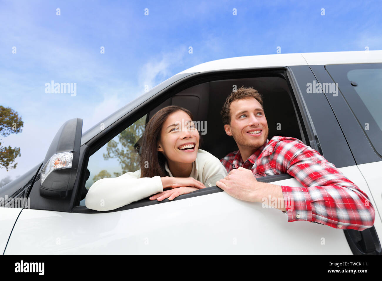 Vie de couple dans la nouvelle voiture looking out window. Jeune homme de conduite et woman enjoying view sur le voyage road trip in nouvelle voiture. Belle jeune jeune couple multiracial. Asian Woman, man. Banque D'Images