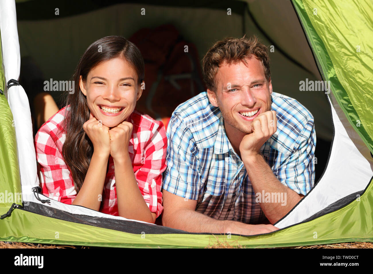 Happy romantic couple camping en tente à la recherche en forêt. Les campeurs smiling happy en plein air dans la forêt de détente. Couple multiracial relaxant après activité de plein air. Asian Woman, man. Banque D'Images