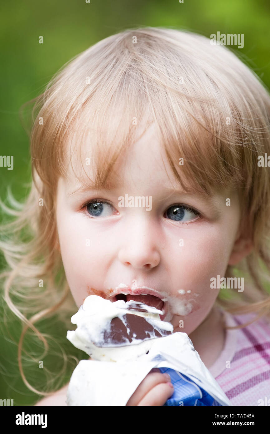 Little girl eating chocolate glace face closeup Banque D'Images