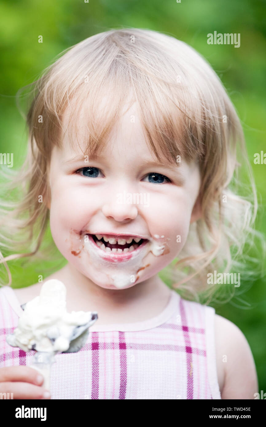 Deux ans blonde girl portrait visage blanc sale avec de la crème glacée Banque D'Images
