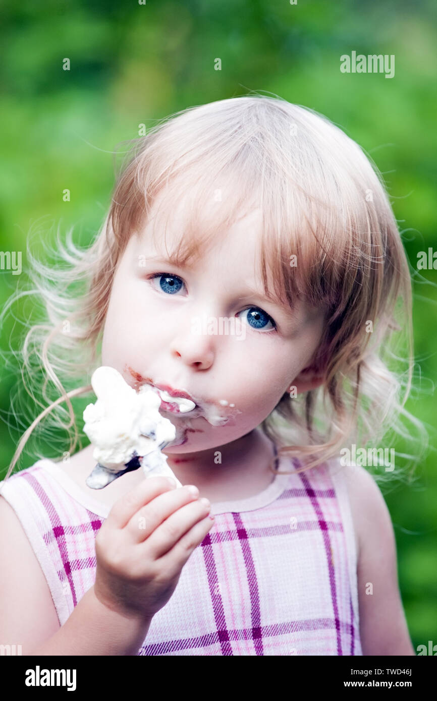 Little girl eating chocolate glace face closeup Banque D'Images