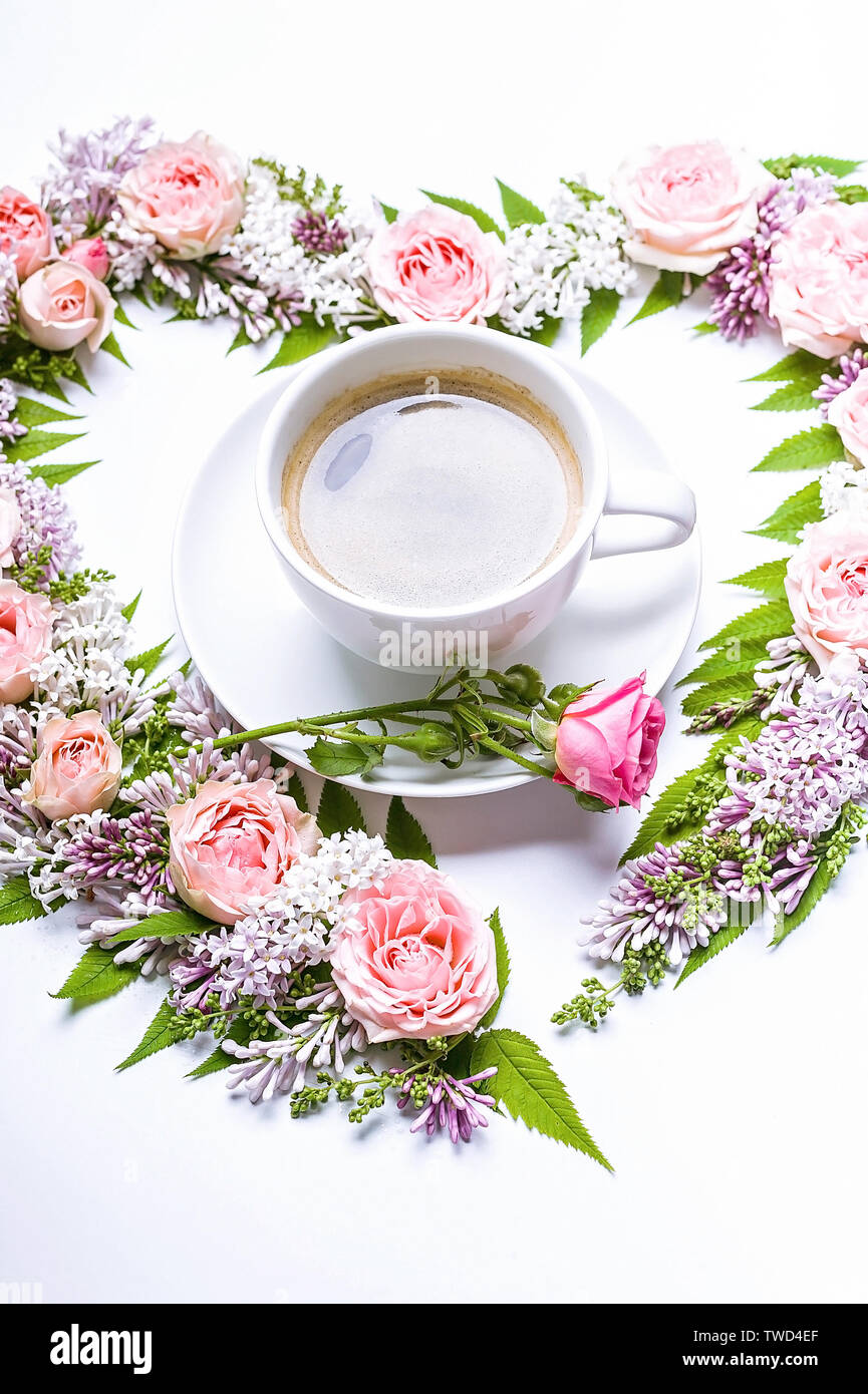 Arrangement de fleurs de mariage. Cadre de fleurs en forme de coeur : rose, lilas, Rowan quitte et tasse de café sur un fond blanc. Motif floral. Banque D'Images