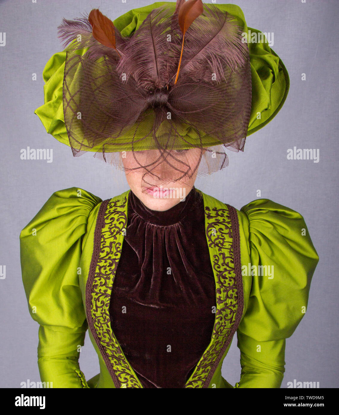 La fin de femme portant un ensemble en soie verte et un grand chapeau Banque D'Images
