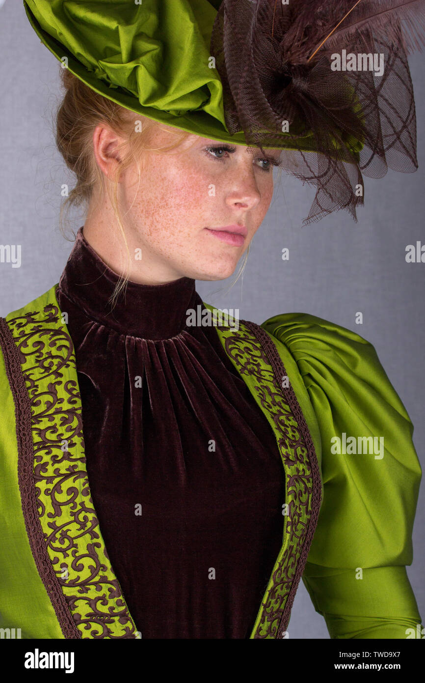 La fin de femme portant un ensemble en soie verte et un grand chapeau Banque D'Images