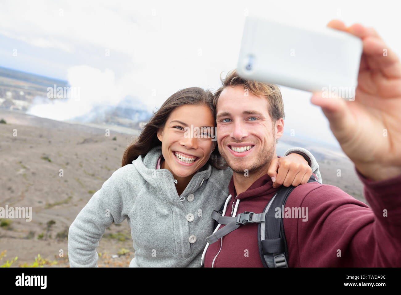 Hawaii - couple sefile par Hawaiian Volcano. Les touristes heureux taking self-portrait with smart phone par cratère Halemaumau dans l'intérieur de la caldeira du volcan Kilauea Hawaii Volcanoes National Park Banque D'Images