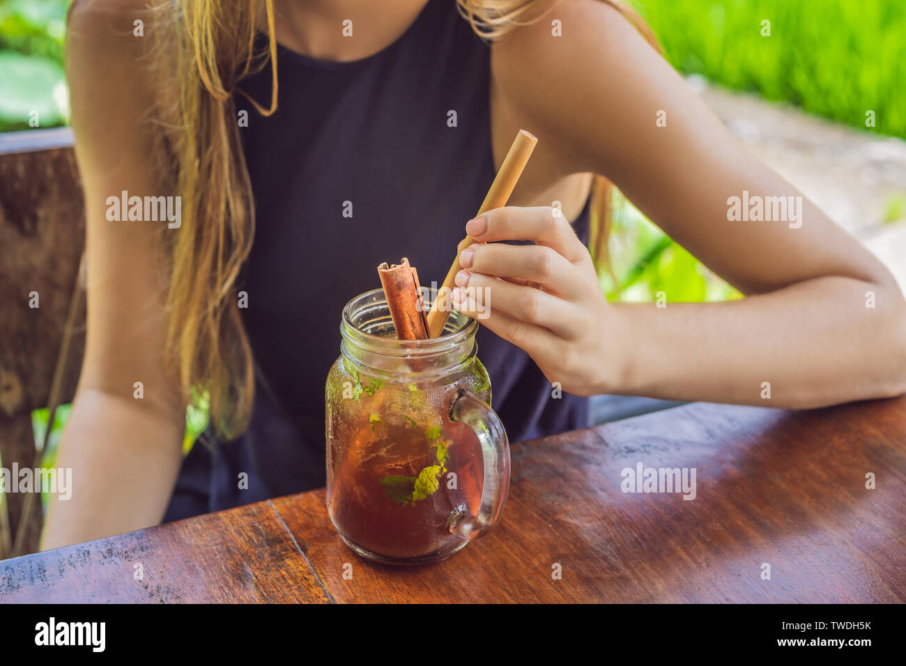 Jeune femme à boire le thé froid avec la cannelle dans champ de riz Banque D'Images