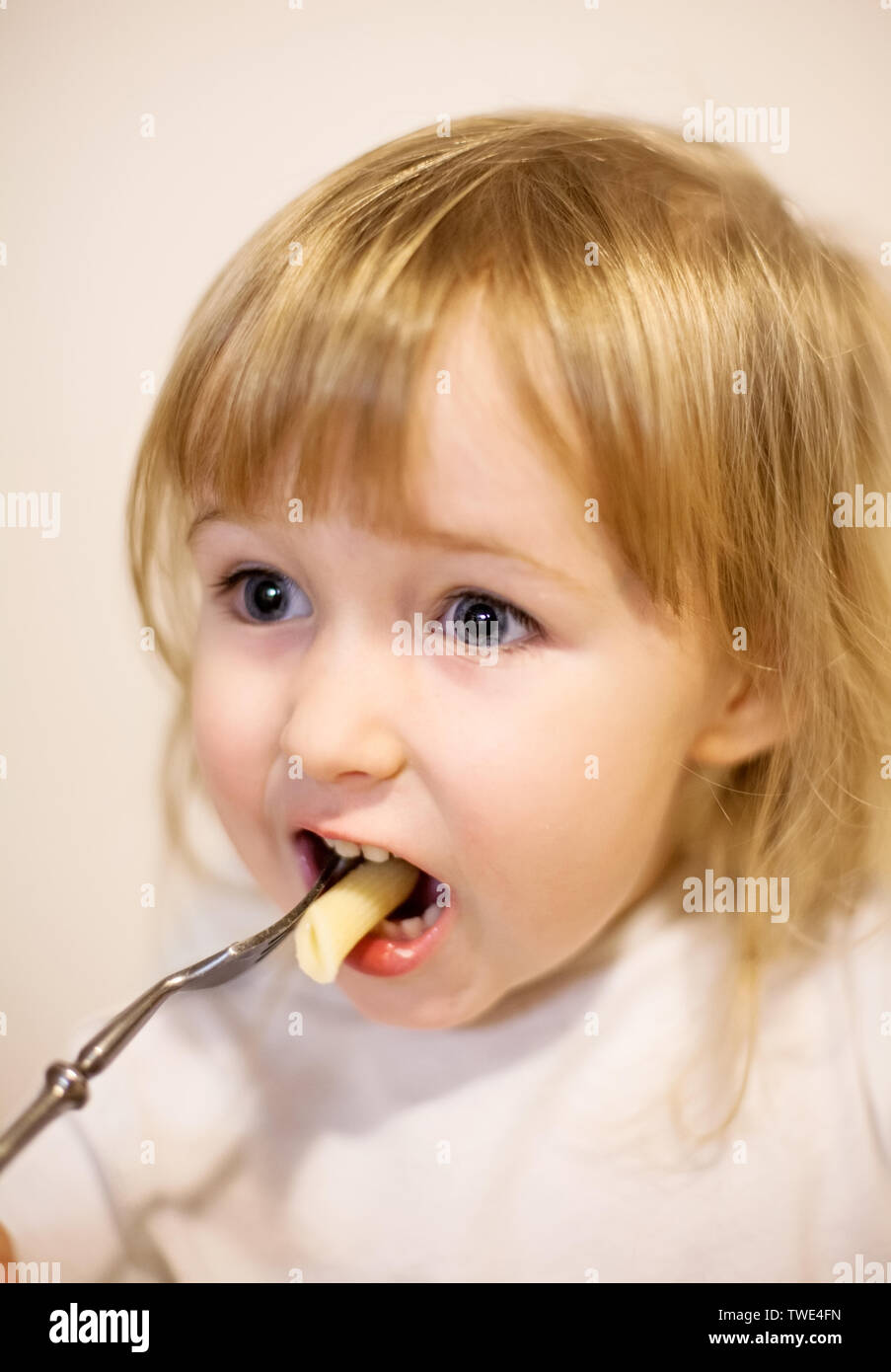 Visage gros plan de little white girl eating pasta par une fourche Banque D'Images