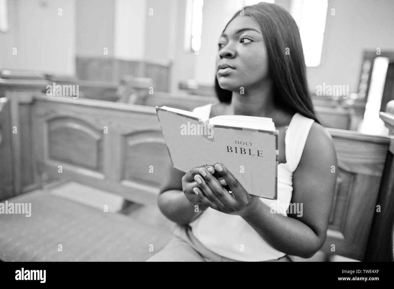 African American Woman priant dans l'église. Croyants médite dans la cathédrale et temps spirituel de la prière. Afro girl tenir sainte bible alors que sitti Banque D'Images
