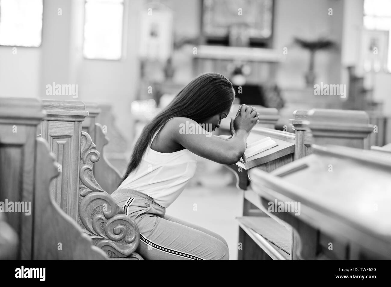 African American Woman priant dans l'église. Croyants médite dans la cathédrale et temps spirituel de la prière. Afro girl mains jointes en position assise Banque D'Images