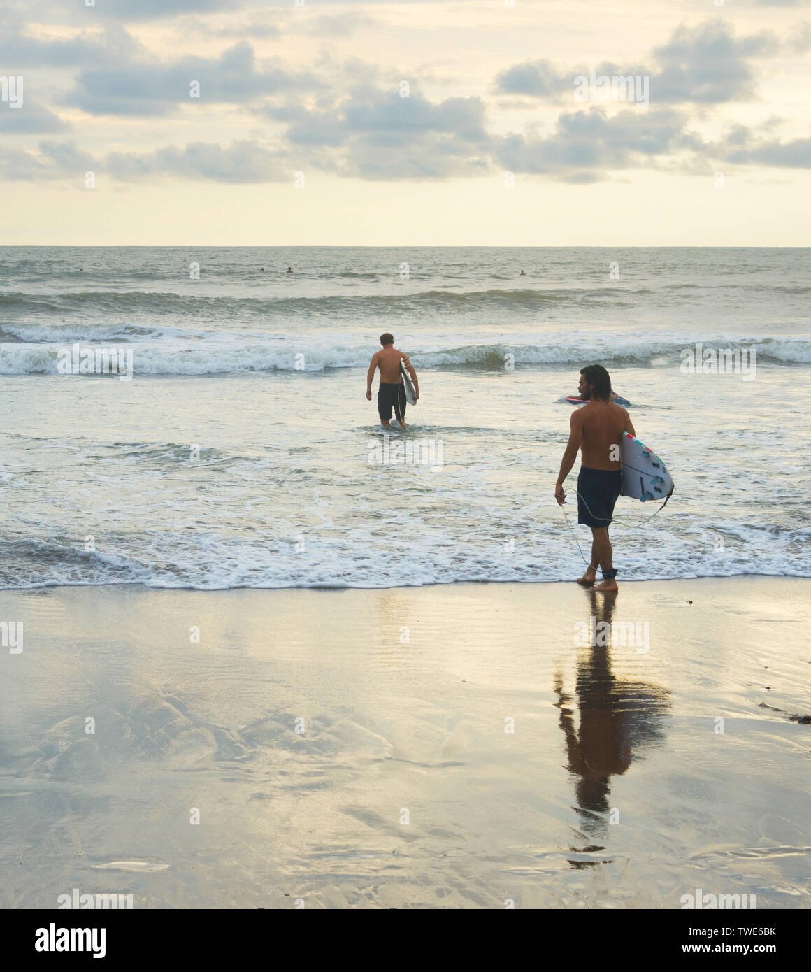 L'ÎLE DE BALI, INDONÉSIE - 12 février 2017 : les hommes avec des planches au coucher du soleil plage Océan surf session pour aller Banque D'Images