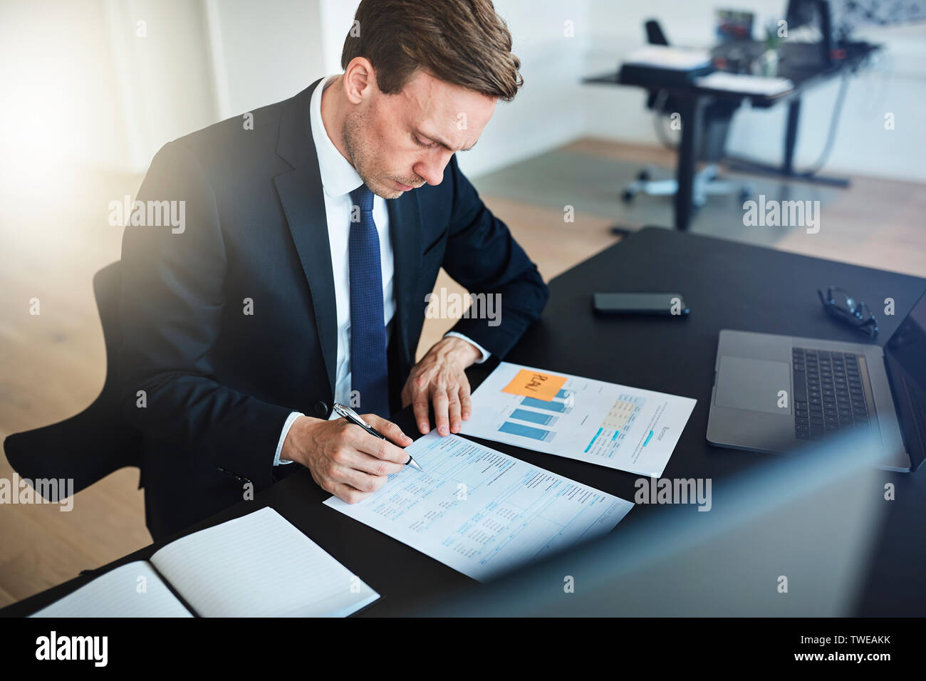 Businessman assis à son bureau dans un bureau moderne et lecture par les formalités administratives et de la signature de documents Banque D'Images