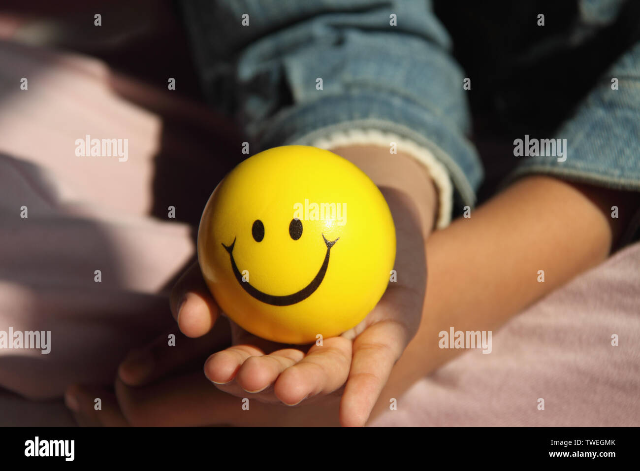 Fille tenant une balle avec visage smiley Banque D'Images