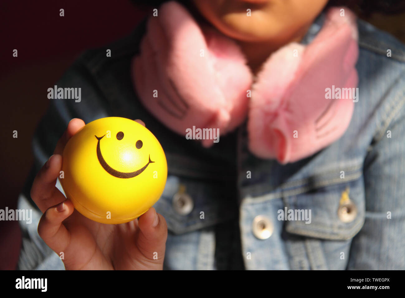 Fille tenant une balle avec visage smiley Banque D'Images