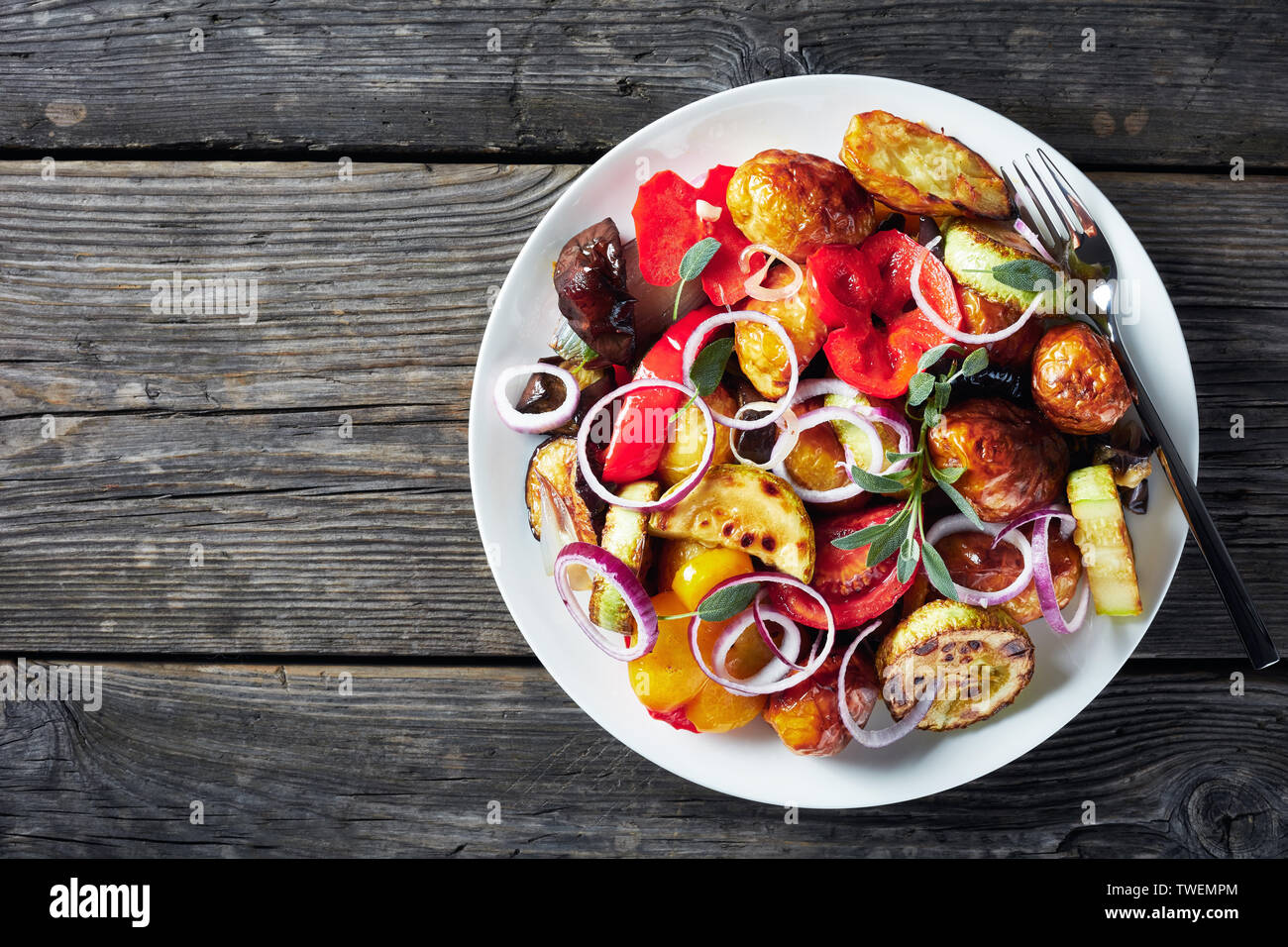 Rôtie au four, légumes chauds - pommes de terre, aubergines, courgettes,  tomates, poivrons sur une assiette blanche sur une table en bois gris,  horizonta Photo Stock - Alamy