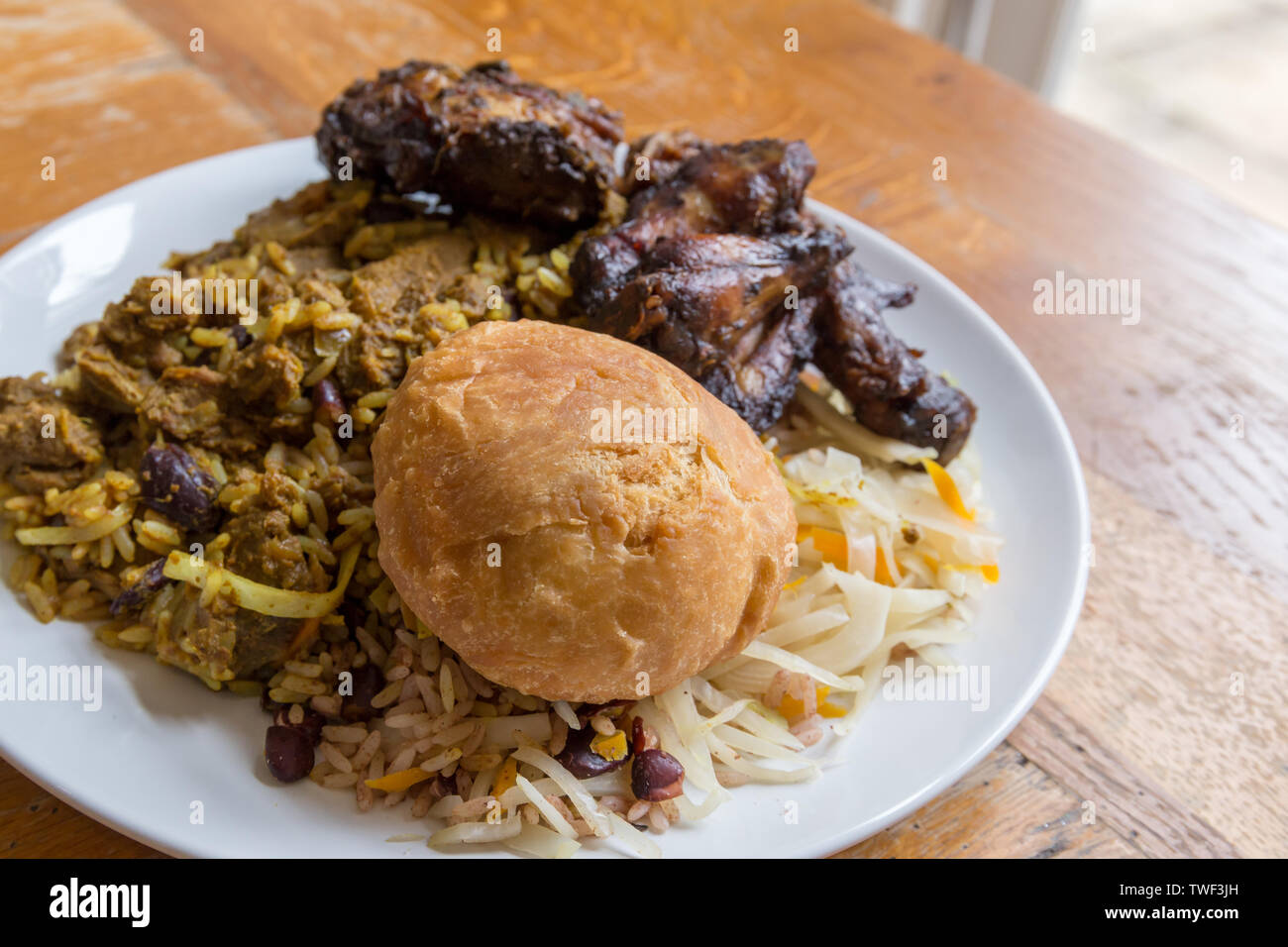 Nourriture jamaïcaine. Chèvre au curry jamaïcain traditionnel, poulet jerk et fried dumpling avec du riz et des pois Banque D'Images