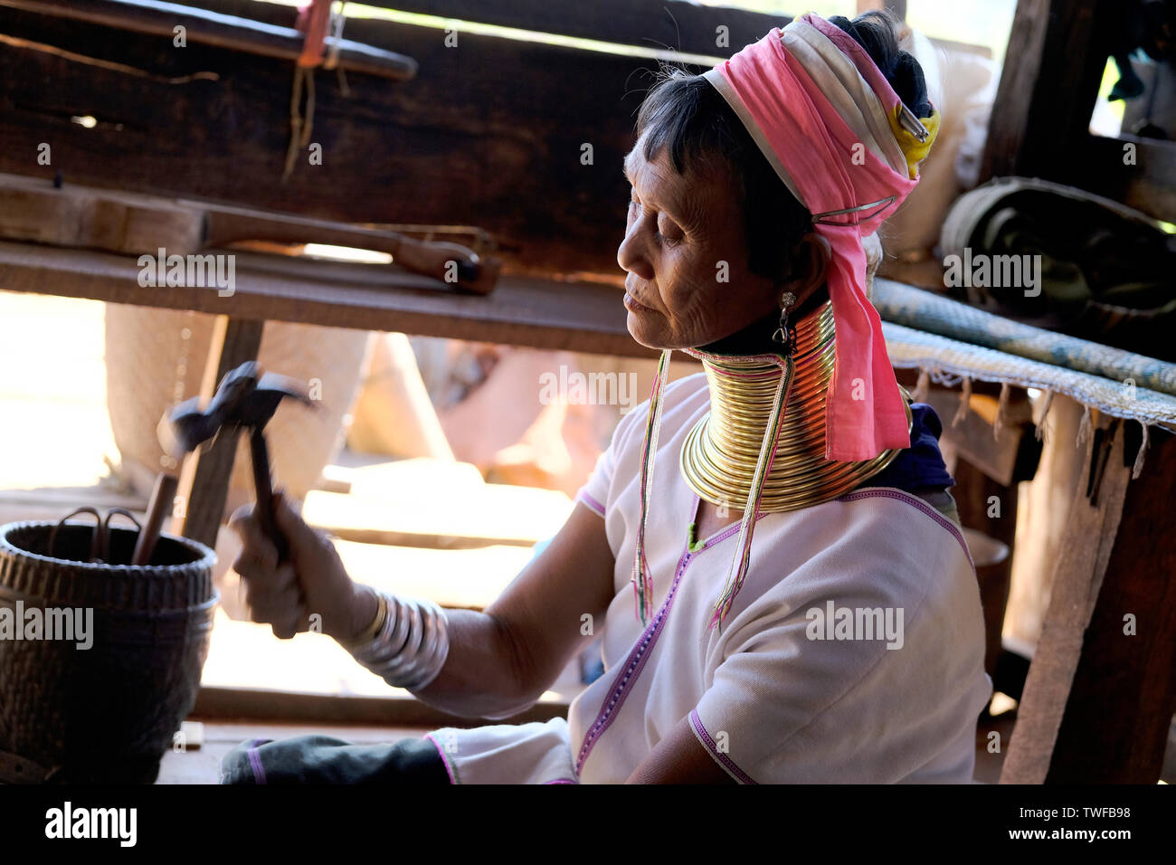 Un long col tribu Karen femme utilise un marteau pour faire des bijoux dans l'État de Kayah au Myanmar. Banque D'Images