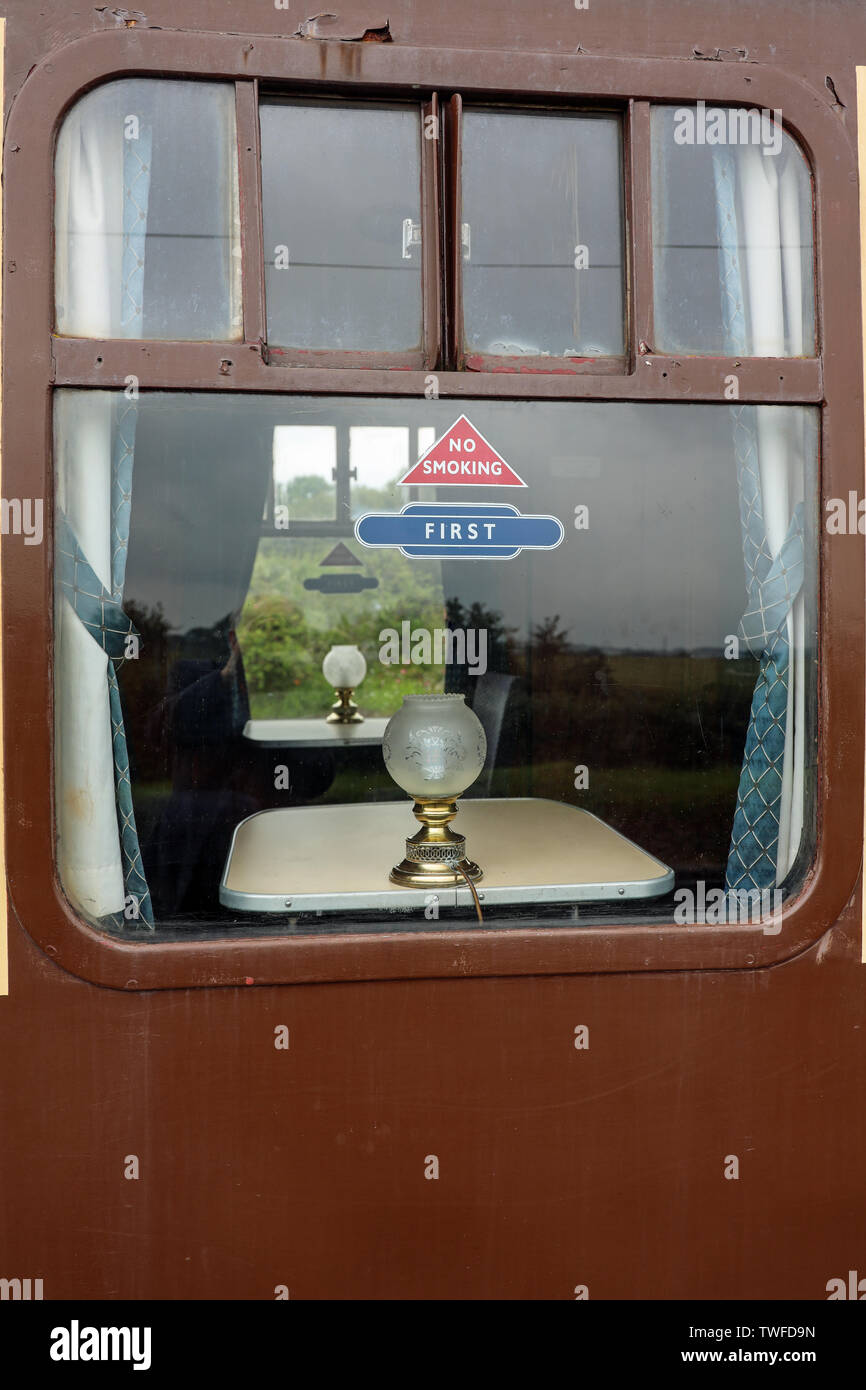 Par la fenêtre d'un compartiment de première classe sur l'entraîneur de l'West Somerset Railway Heritage. Lampes de table et de ne pas fumer triangle. Nostalgique. Banque D'Images