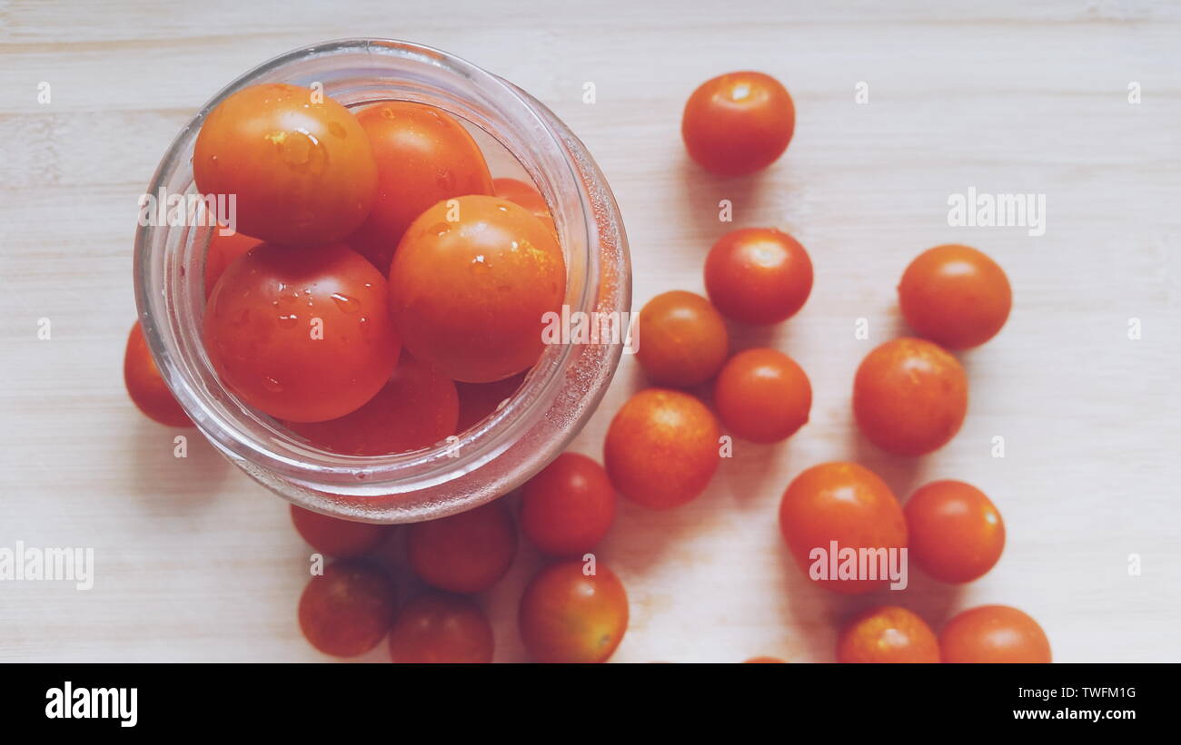Tomates cerises sur une table et dans un bocal en verre Banque D'Images