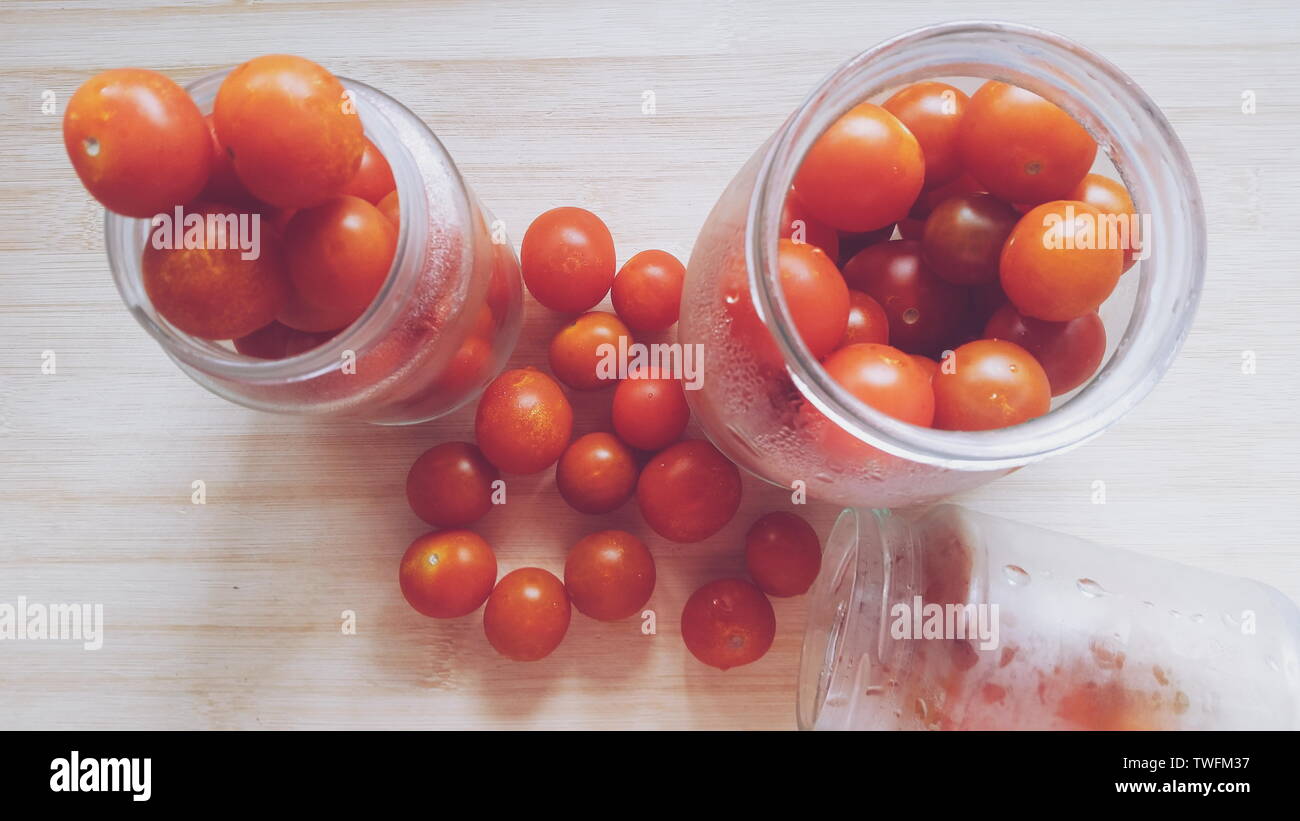 Tomates cerises sur une table et dans un bocal en verre Banque D'Images