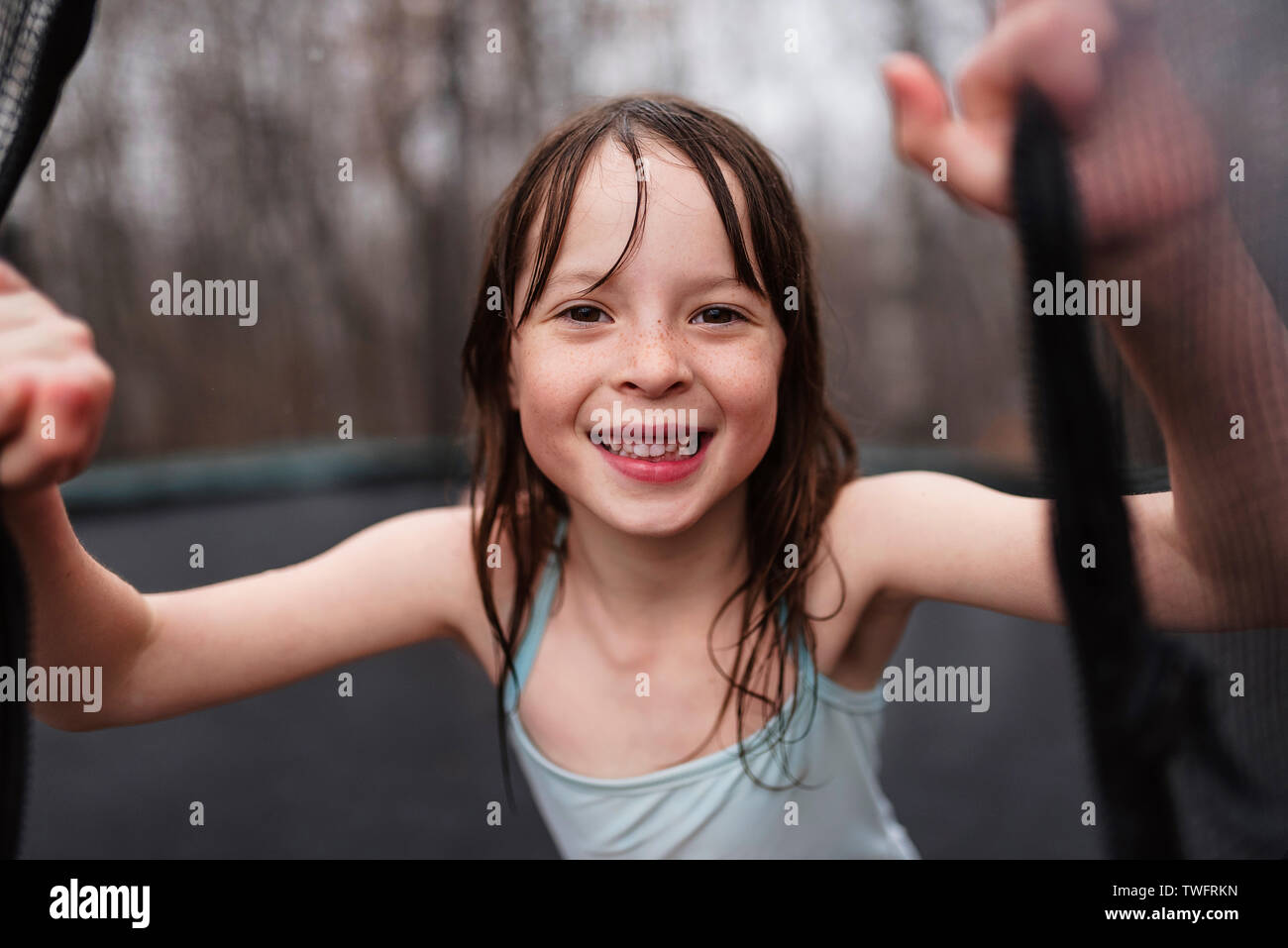 Smiling girl jouant sur un trampoline dans la pluie, États-Unis Banque D'Images