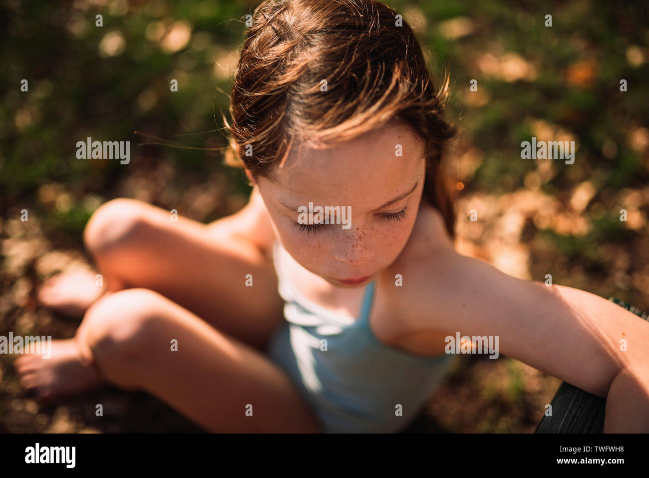 Fille dans un maillot de bain assis sur l'herbe, United States Banque D'Images