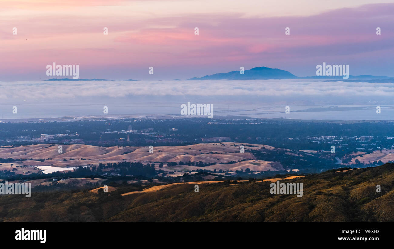 Des nuages et du brouillard au crépuscule sur la Silicon Valley et la région de la baie de San Francisco, l'Université de Stanford visible sous une couche de nuages ; Mt Diablo dans la b Banque D'Images