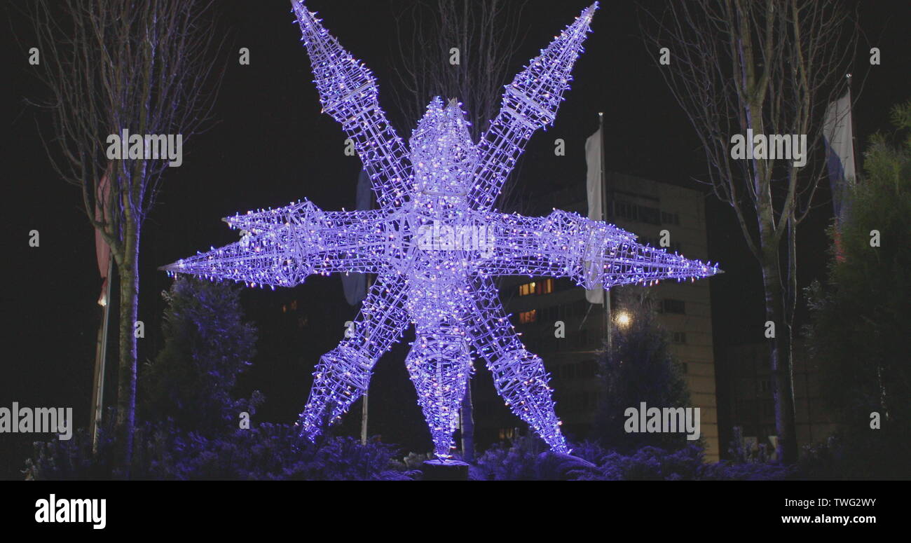 Illumination de Noël sous la forme d'un flocon de neige sur la rue dans la soirée Banque D'Images