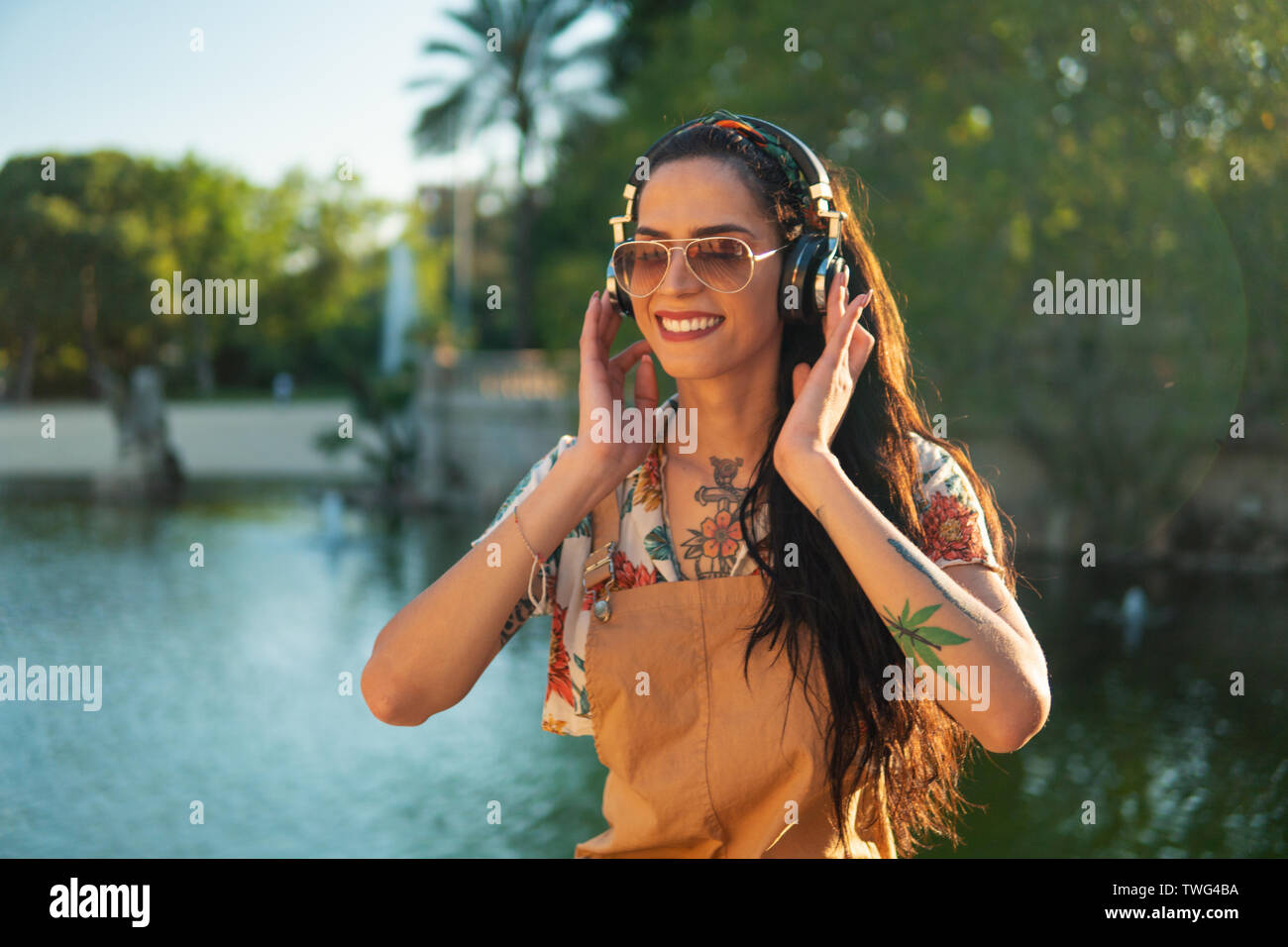 Modèle transgenre portant des lunettes de soleil dans le vert du parc Banque D'Images