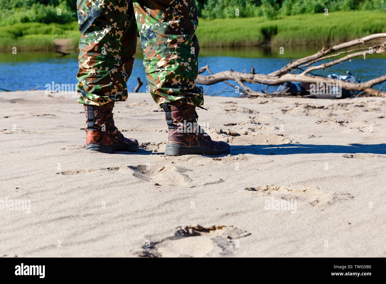 Les pieds des hommes dans les chaussures sur le sable au bord de la rivière Banque D'Images