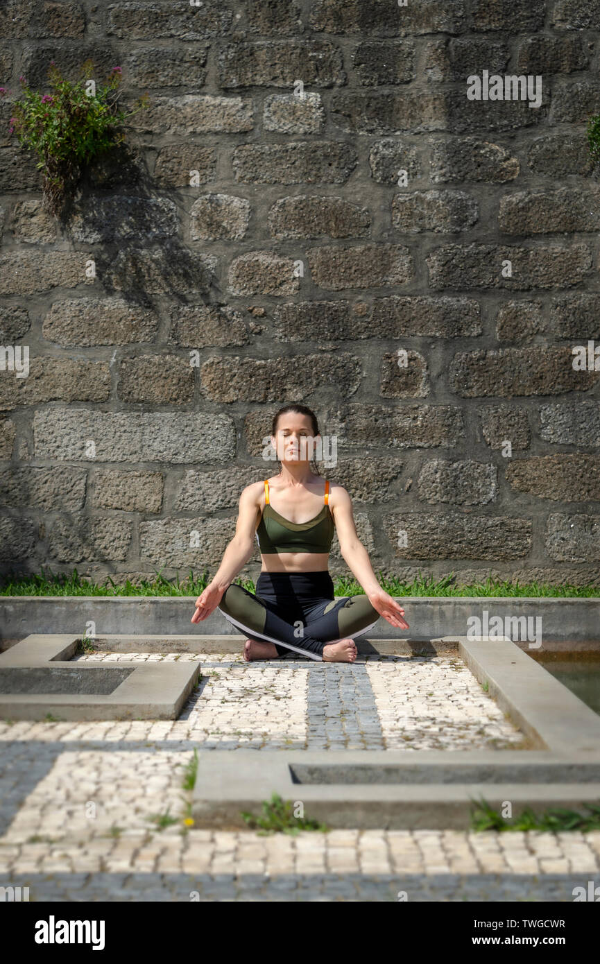 Femme méditant pratiquant le yoga à l'extérieur dans un jardin fleuri Banque D'Images