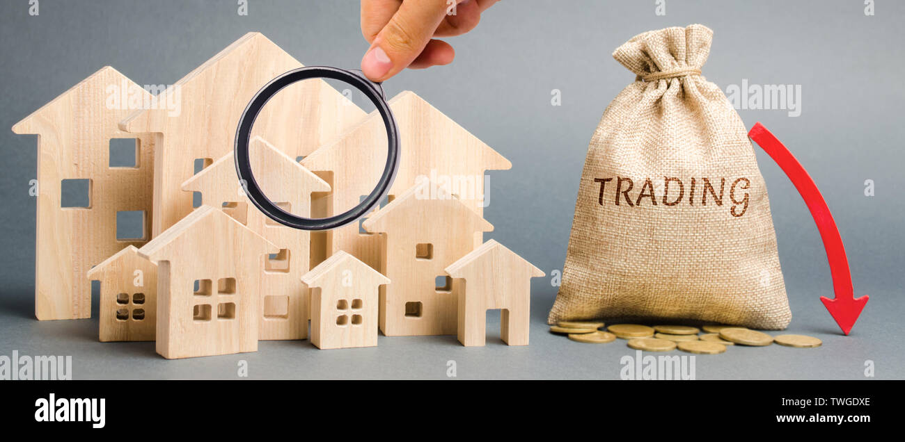 Un sac d'argent avec le mot Trading, une flèche vers le bas et les maisons en bois. Le concept de la baisse de la demande pour l'achat de maison. L'offre réduite. Faible liquidité. Fal Banque D'Images