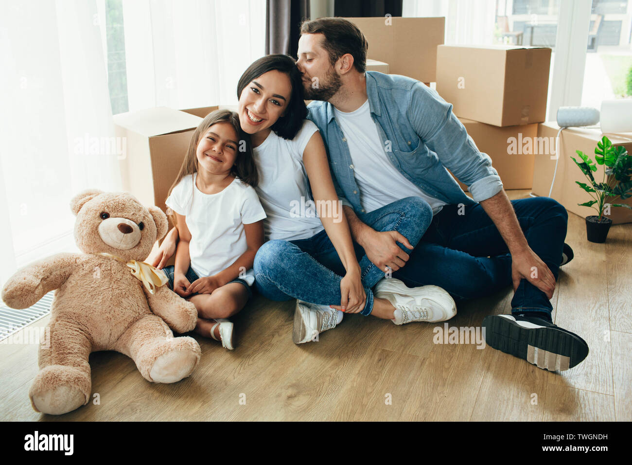 Jolie famille déménager. Couple avec enfant assis sur leur nouvel appartement avec de nombreux cartons Banque D'Images