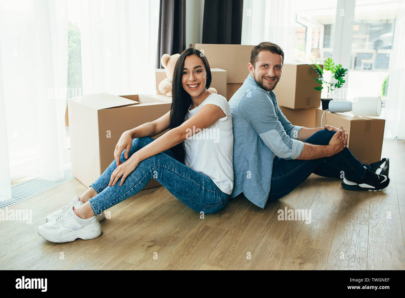 Couple heureux déménagement nouvelle maison. Assis sur leur parole dans leur nouvelle maison avec de nombreux cartons on background Banque D'Images