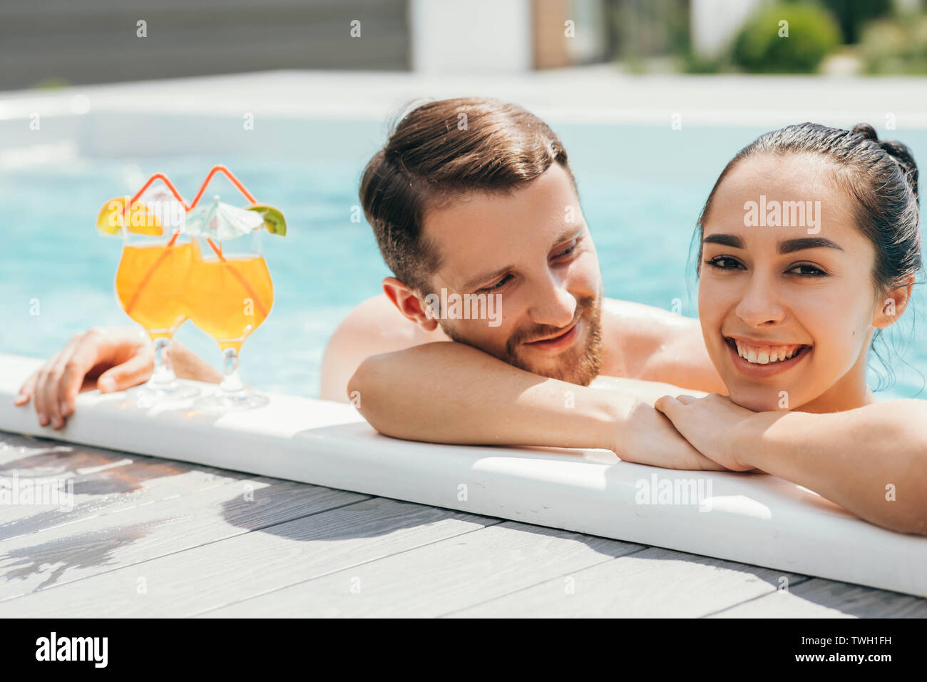 Heureux couple hétérosexuel est bien reposé avec des cocktails tandis que dans la piscine. Repos d'été Banque D'Images