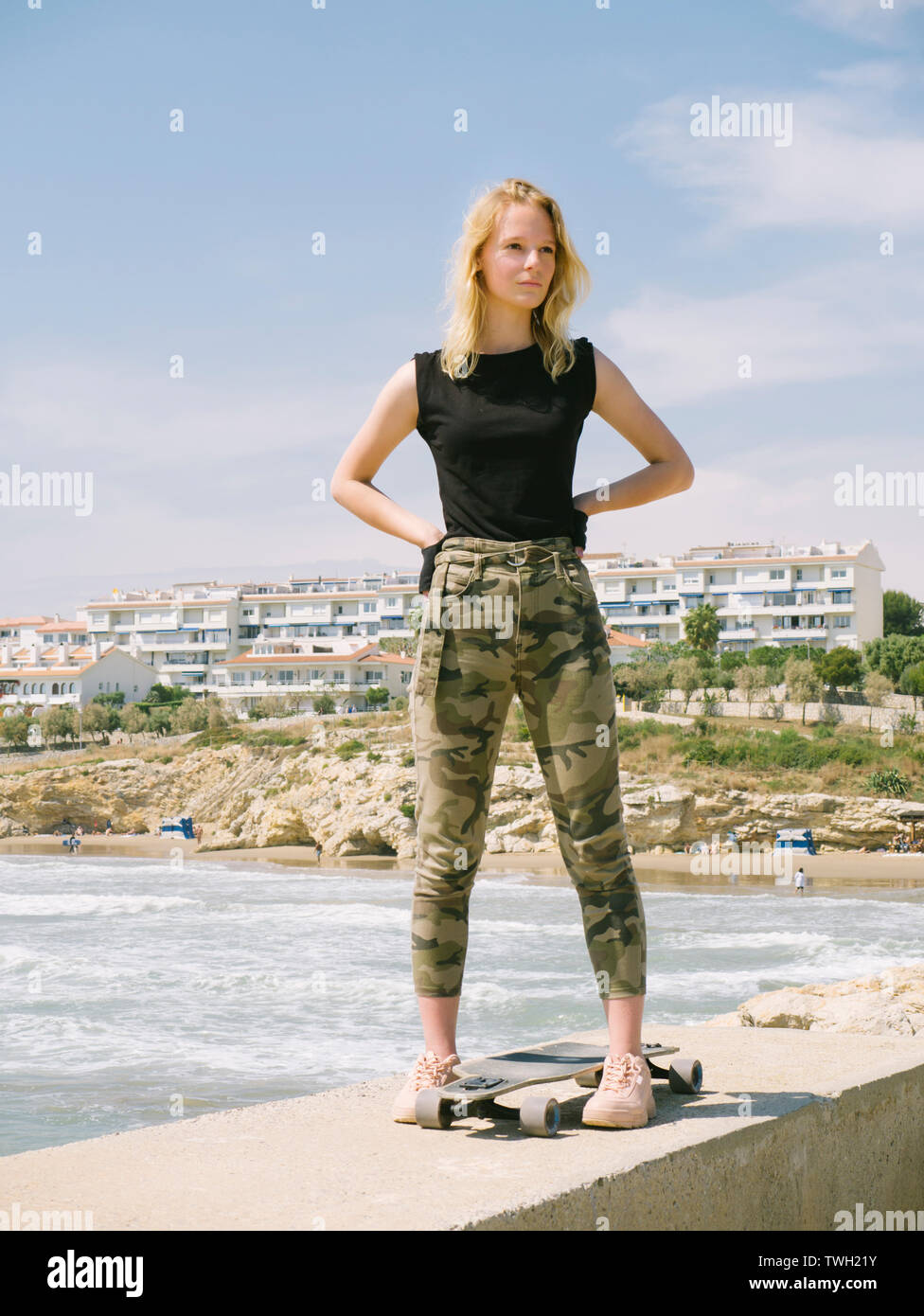 Belle et le style jeune fille posant avec une planche à roulettes au front de mer. Girl enjoying de liberté. Banque D'Images