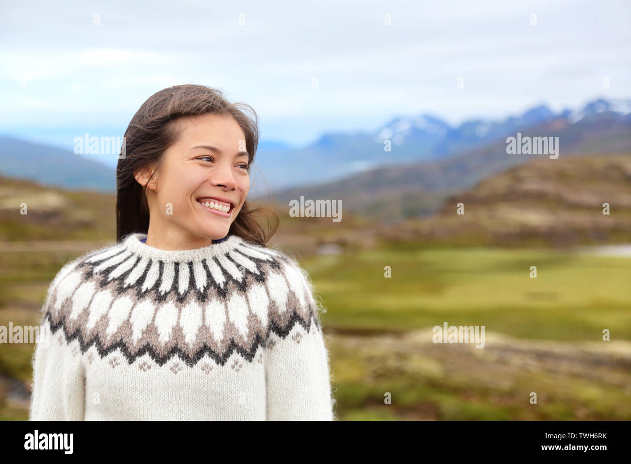 Femme sur l'Islande en islandais pull. Portrait of Girl Happy smiling outdoors dans la nature islandaise portant chandail. Joli modèle féminin asiatique multiracial du Caucase Banque D'Images