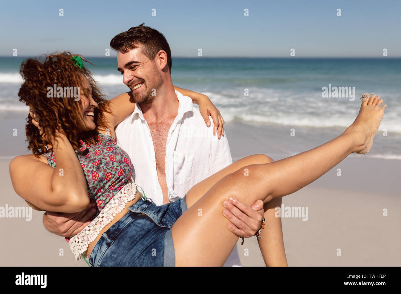 Femme Jeune homme tenant dans ses bras sur la plage au soleil Banque D'Images