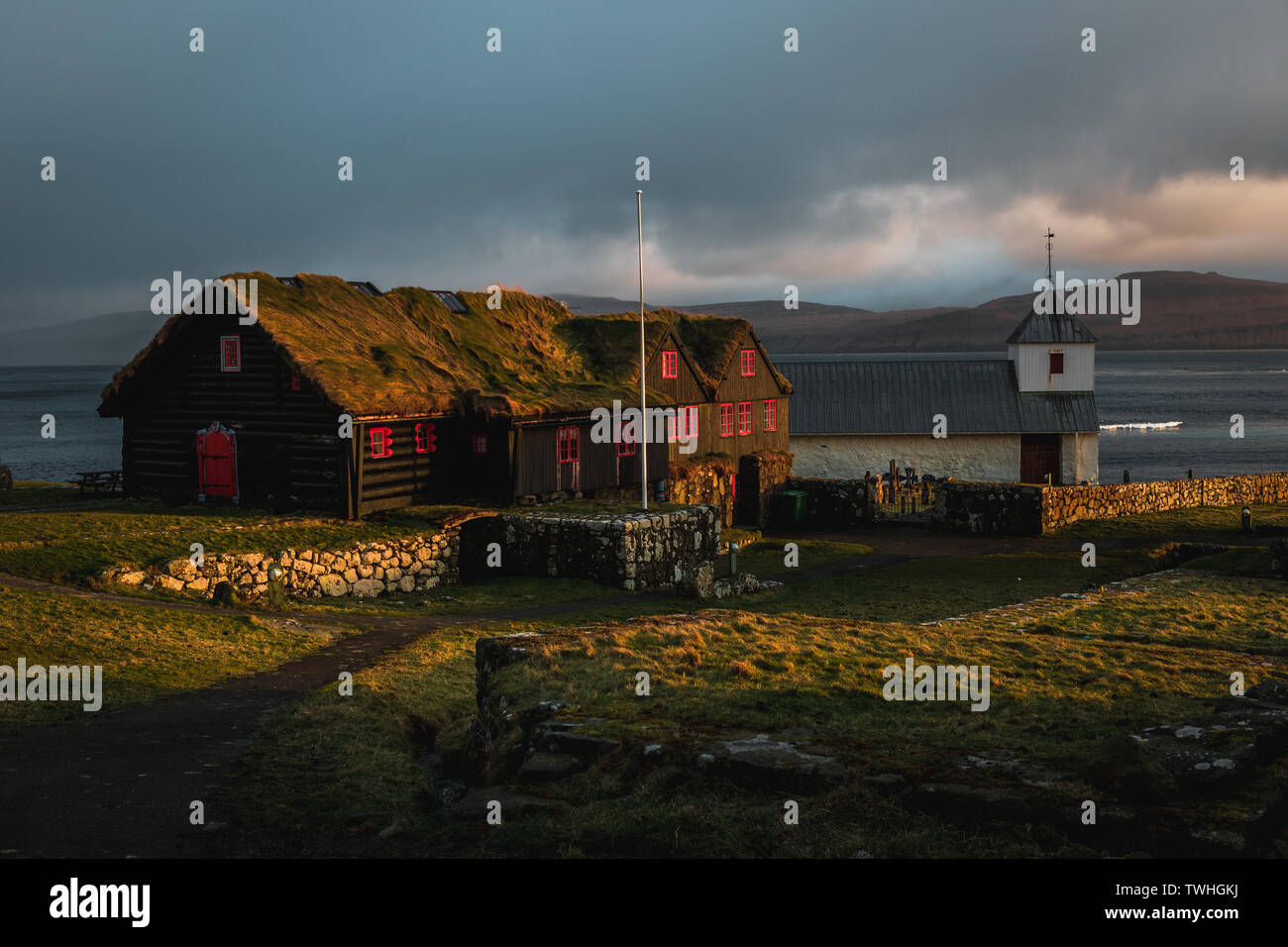 Noir et rouge typique des maisons en bois des îles Féroé avec toit d'herbe comme repéré pendant le coucher du soleil dans le village de Kirkjubour au printemps (îles Féroé) Banque D'Images