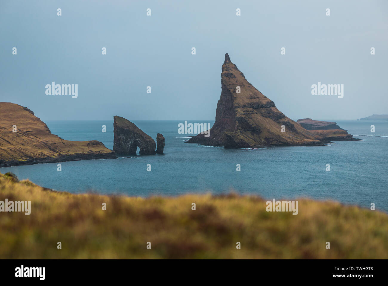 Vue panoramique de l'île de Tindholmur Drangarnir et prises au cours de randonnée le long des côtes des îles Féroé moody lors d'une matinée de printemps (îles Féroé, Danemark) Banque D'Images