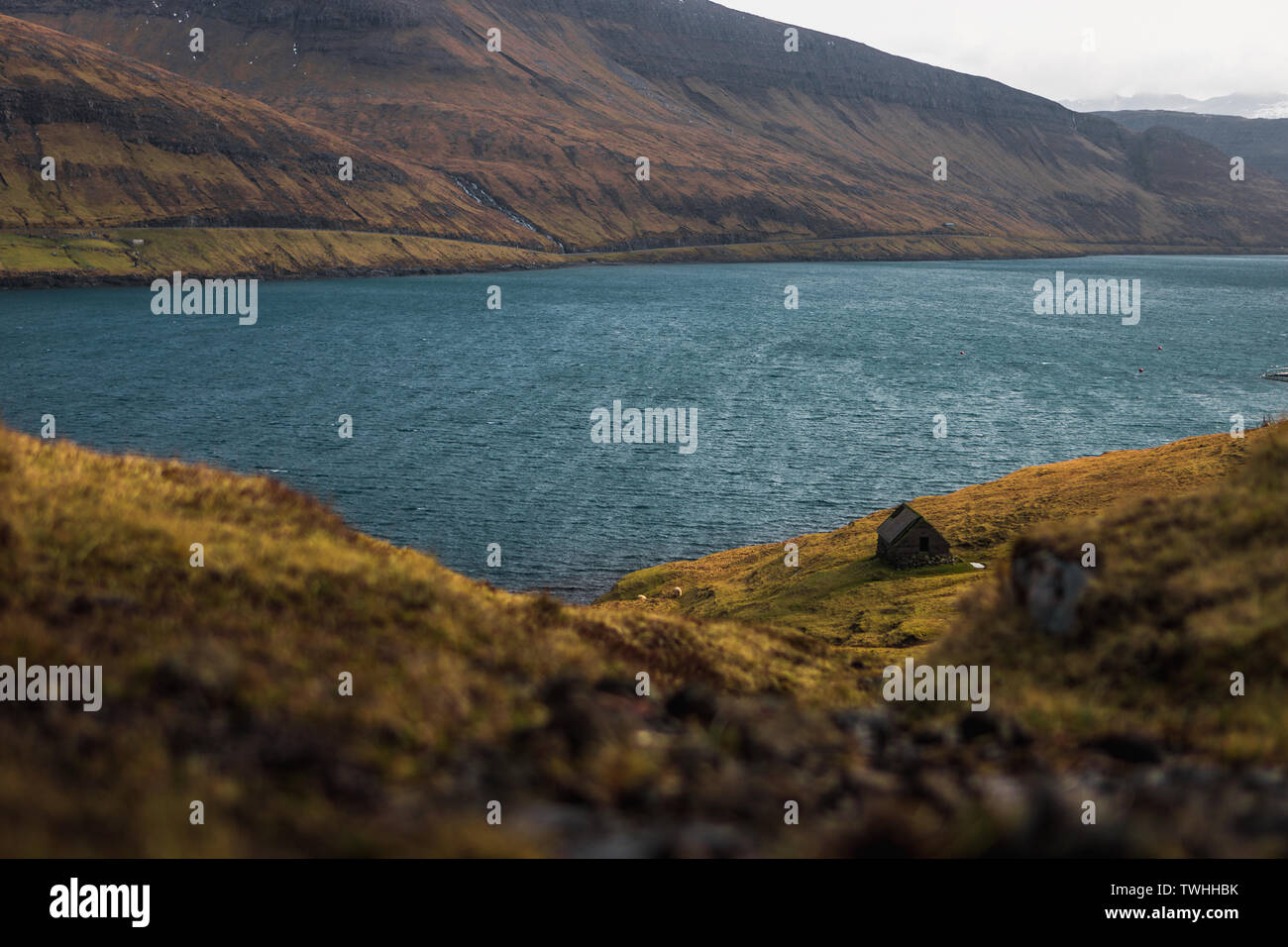 Petite vieille cabane de pêcheur repéré en féroïen fjord sur la randonnée à vélo vers Dranganir Tindholmur et cliff island au printemps lever du soleil (îles Féroé) Banque D'Images