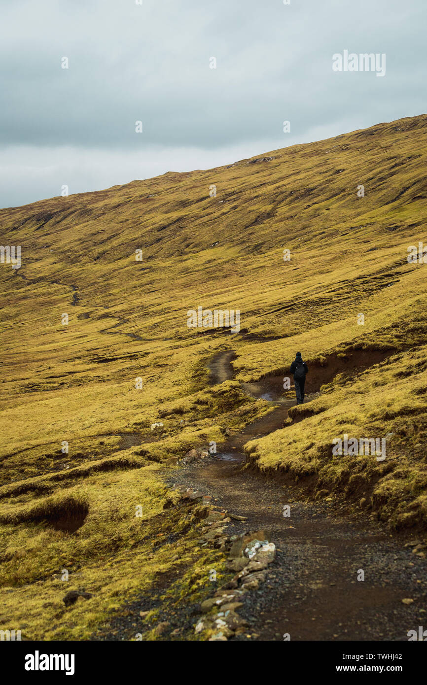 Randonnée randonneur solitaire sur la route vers Sorvagsvatn Bosdalafossur Lac et cascade au cours d'une soirée de printemps moody (îles Féroé, Danemark, Europe) Banque D'Images