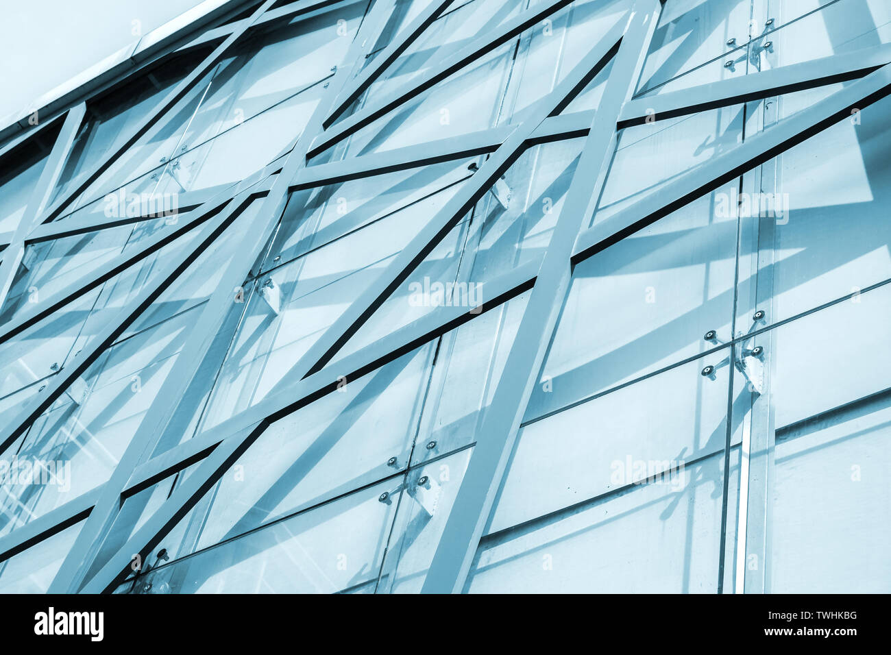Résumé L'architecture commerciale, l'arrière-plan la façade de l'immeuble de bureau avec structure en acier et motif géométrique des panneaux de verre. Photo dans les tons bleus Banque D'Images