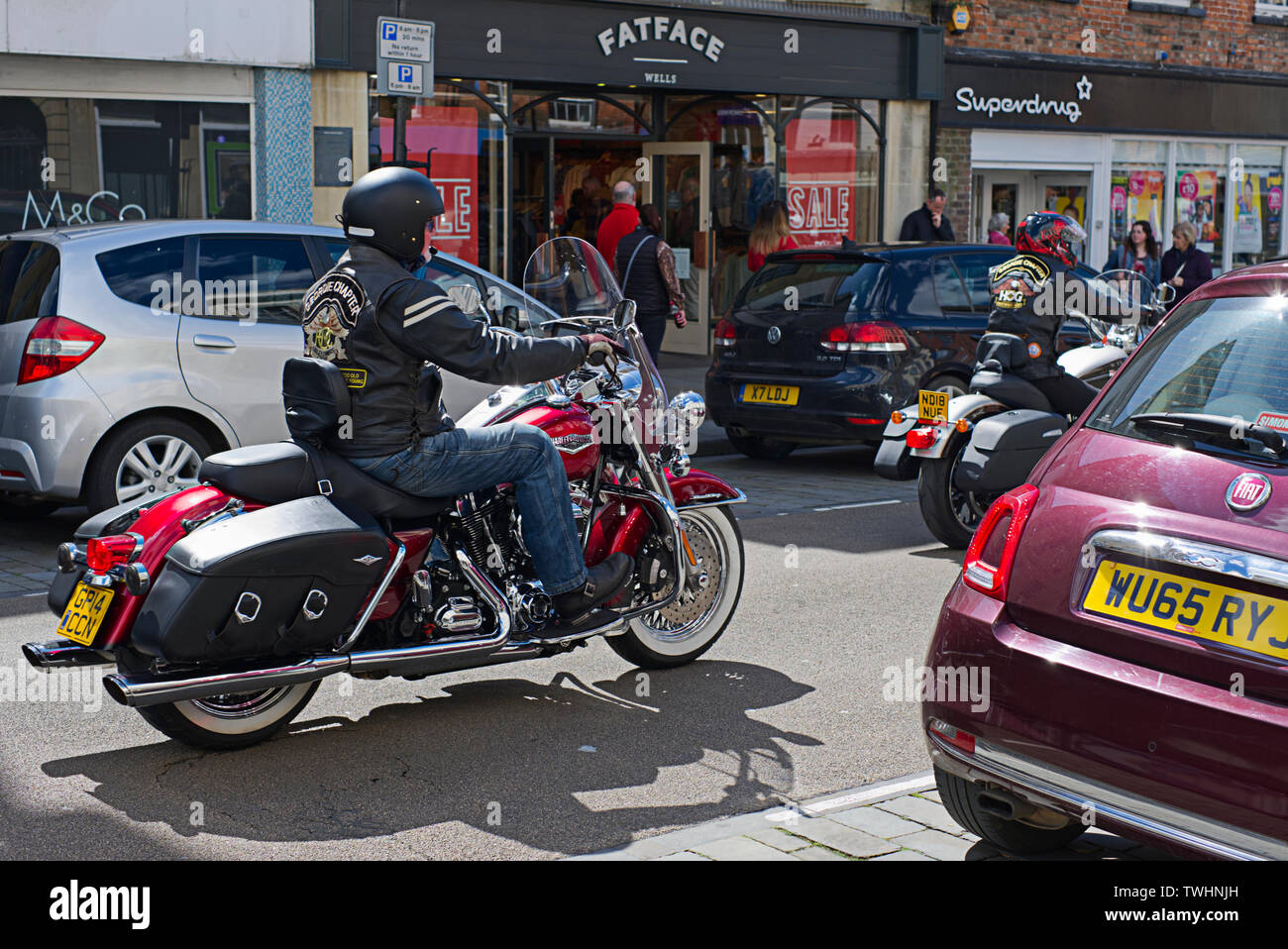 Un membre de la Harley Davidson du groupe du propriétaire et sa circonscription 2014 Harley-Davidson FLHRC Road King sur les puits High-Street, Wells, Somerset Banque D'Images
