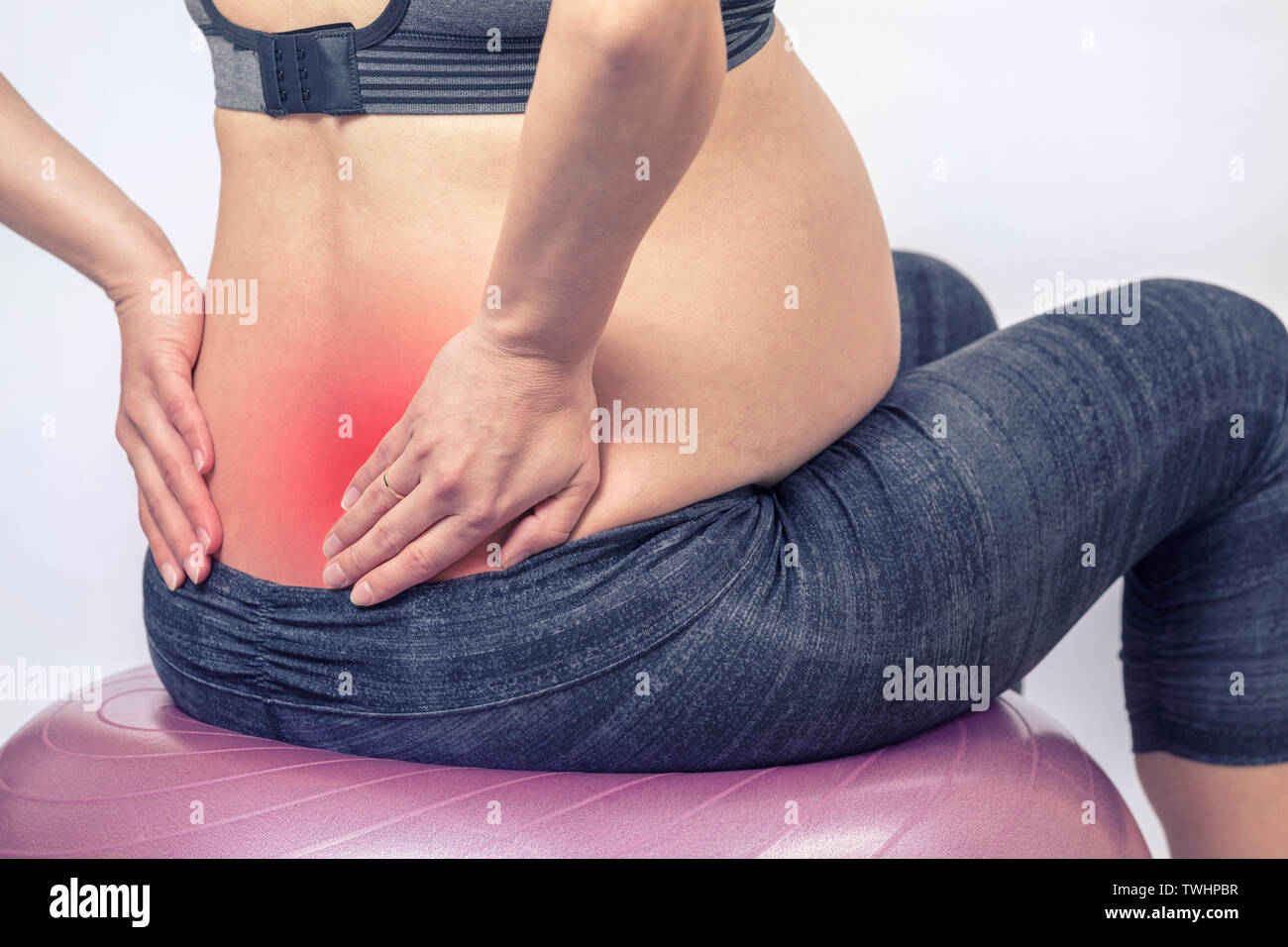 Douleurs et douleurs. Une femme enceinte active fait de l'exercice dans le centre de remise en forme de la salle de yoga. La jeune mère s'attend à ce qu'elle tient la main sur le dos et s'assoit sur une forme physique Banque D'Images